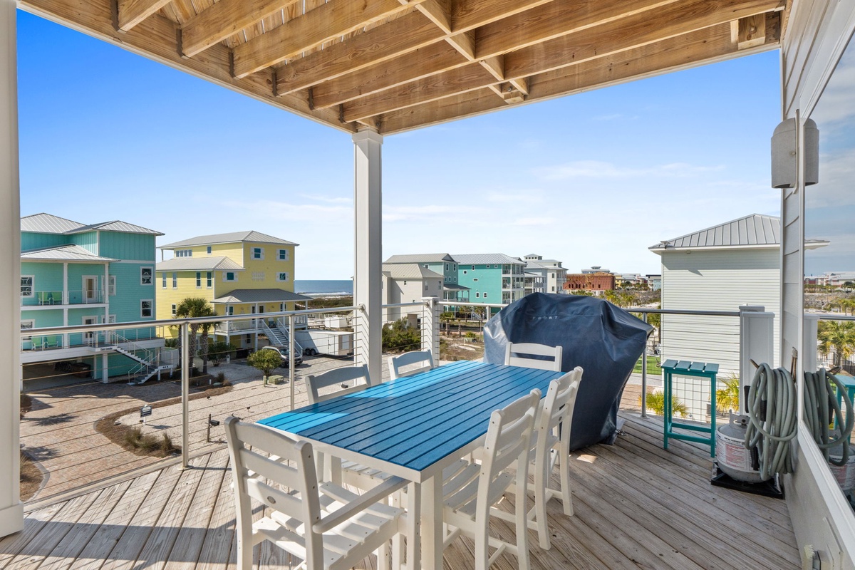 Relax on your private covered deck with ocean views and colorful coastal homes creating a perfect beach vacation backdrop.