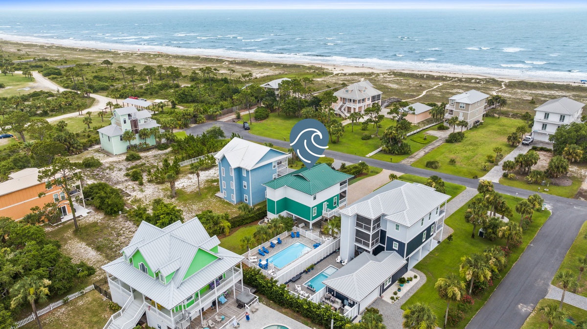 Beachfront coastal community featuring vacation homes with pools, palm trees, and direct ocean access along pristine sandy shores.