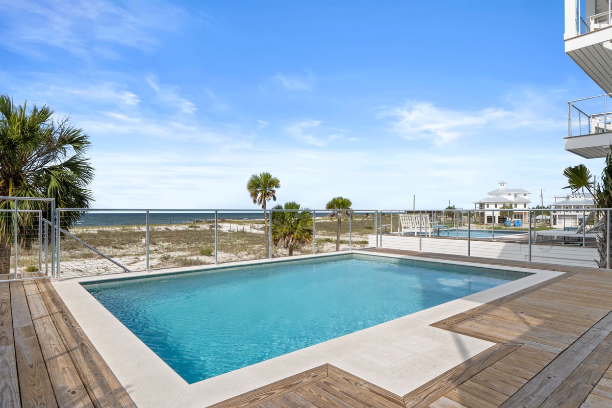 Coastal property with private pool, glass barrier, and sandy beach access just steps away.