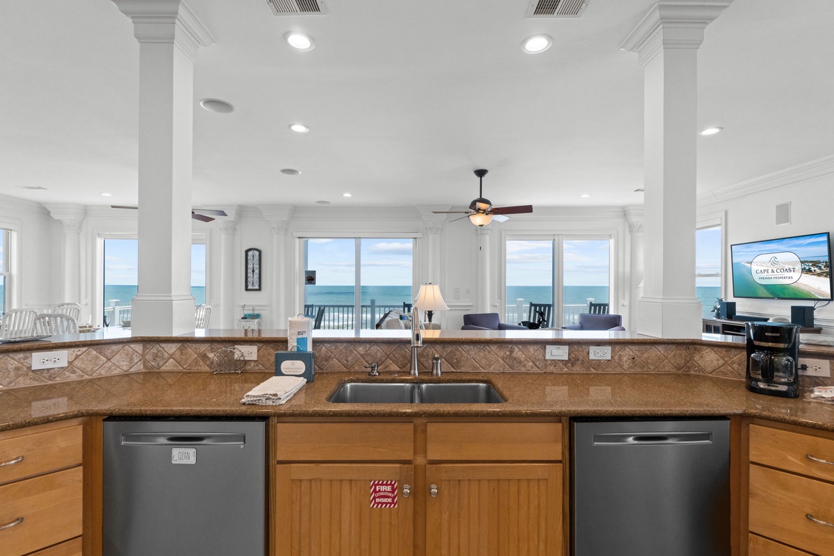 A breathtaking beachfront kitchen setting features granite counters, double dishwashers, and an open-concept design. Floor-to-ceiling windows showcase stunning ocean views, connecting your cooking space to the calming waves beyond.