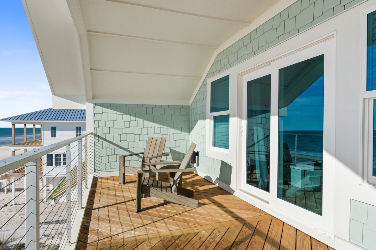 Relax on your private wooden deck with comfortable seating while gazing through expansive windows at breathtaking coastal views.