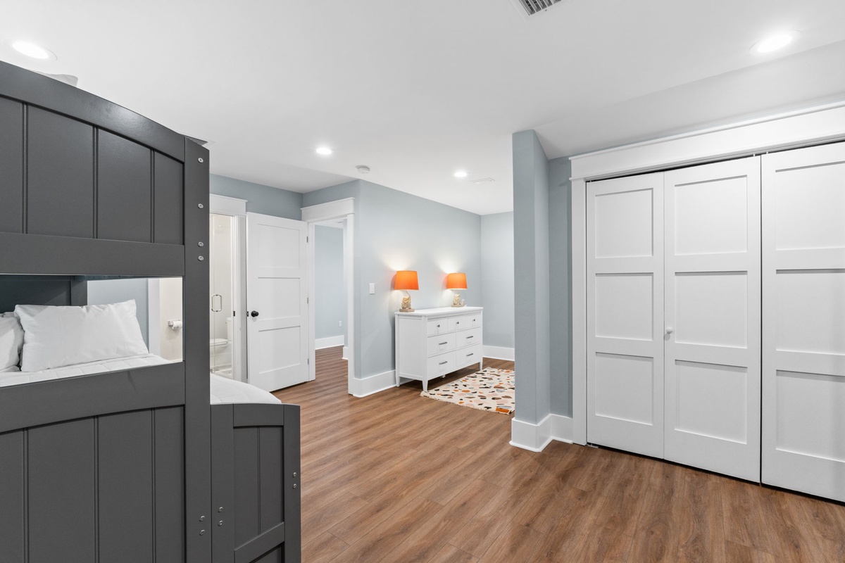 Your spacious bedroom features warm hardwood floors, modern gray bunk beds, and abundant storage with sleek white wardrobes—perfect for families settling in comfortably.