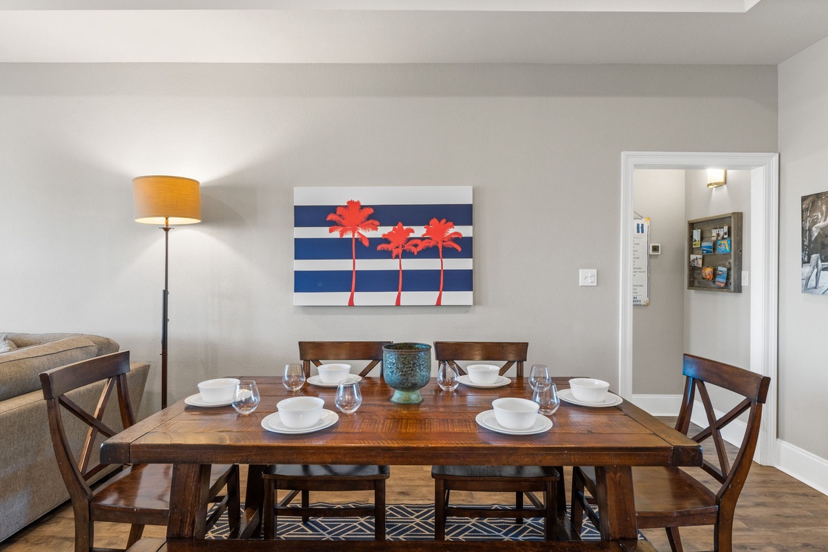Gather around this inviting dining table where your meals become memorable moments, featuring warm wood tones and cheerful coastal artwork.