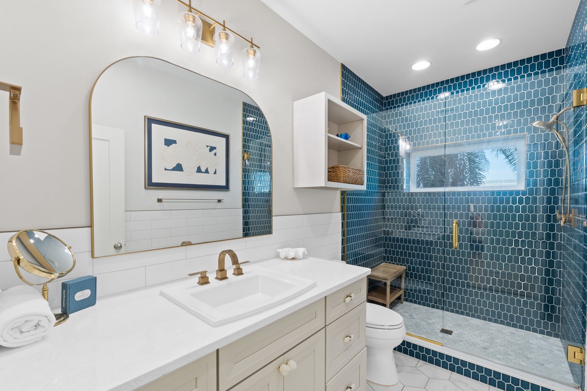 Unwind in your elegantly designed bathroom featuring stunning blue tile work, gold fixtures, and a luxurious walk-in shower.