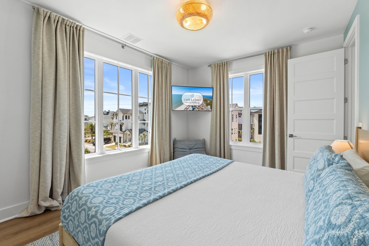 Unwind in your light-filled coastal bedroom with charming neighborhood views. Soft blue accents and natural textures create a soothing retreat after beach days.