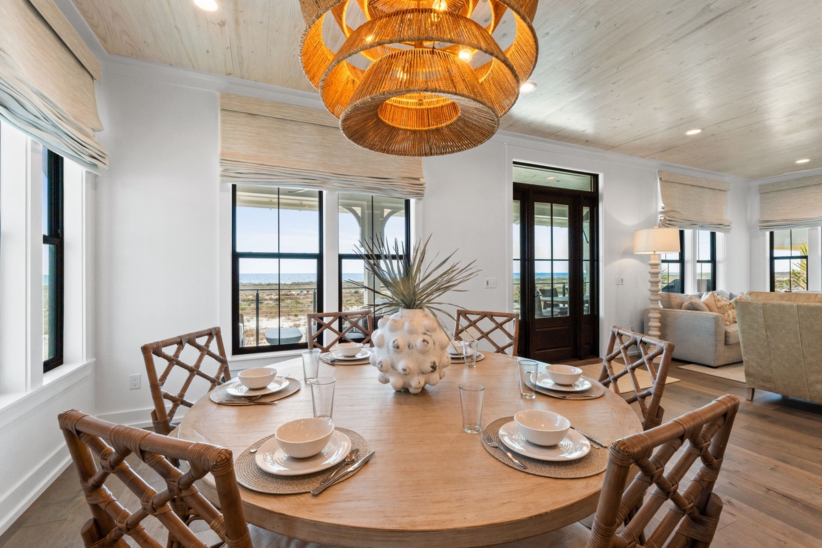 Gather around this elegant dining table for memorable meals, with stunning natural light streaming through panoramic windows and a striking woven pendant overhead.