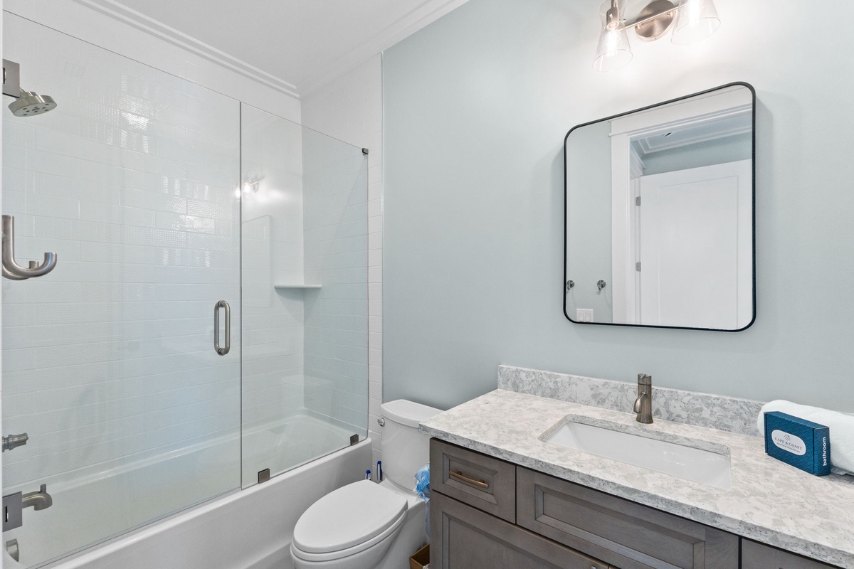 Step into your spa-like retreat with soft blue walls, gleaming marble counters, and a sleek glass-enclosed tub. Everything you need to unwind awaits.