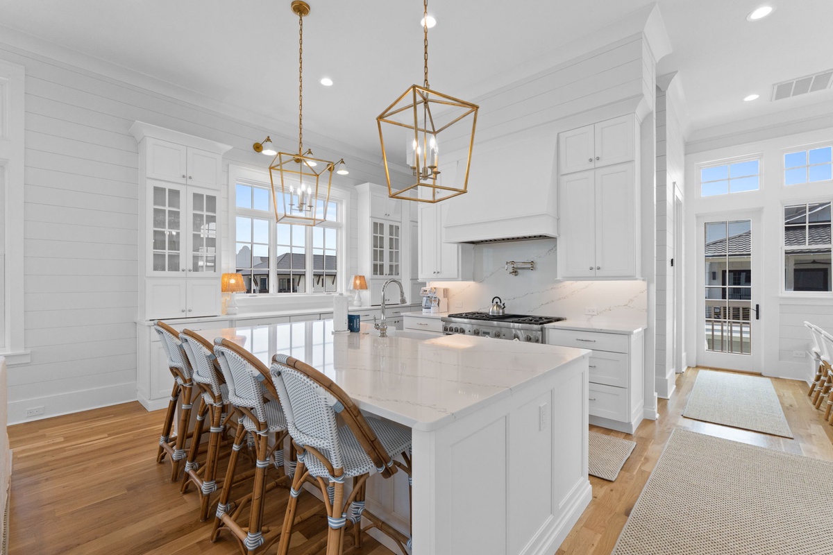 Bright white cabinetry, gleaming countertops, and elegant gold pendant lighting create your dream kitchen. Picture yourself gathering around the spacious island for morning coffee or evening conversations.