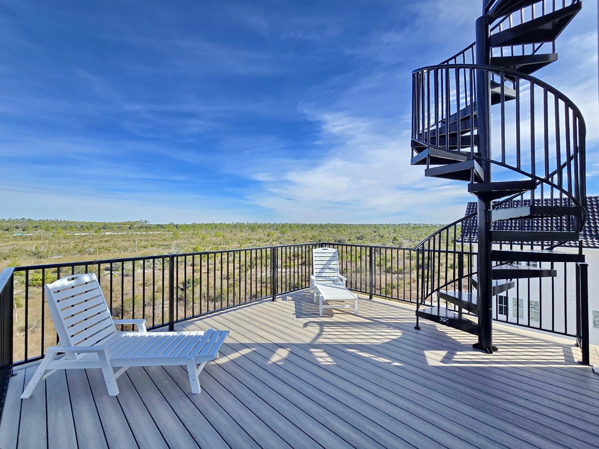Unwind on your private deck with panoramic views, where comfortable lounge chairs invite afternoon relaxation under endless blue skies.