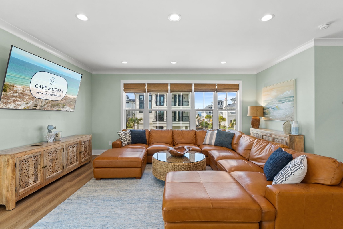 Sink into the luxurious leather sectional and enjoy your favorite shows on the large TV, all while natural light pours through expansive windows. This coastal-inspired living room offers the perfect space to unwind and reconnect.