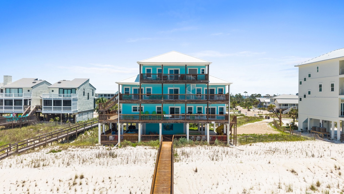A beachfront property featuring direct access via a wooden walkway stretching across pristine white sand and coastal dunes to the shoreline.