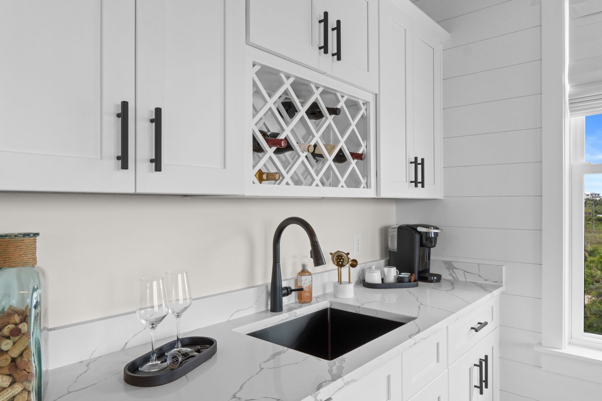 Elegant white cabinetry frames a built-in wine rack and sleek marble countertops, with a coffee maker ready for your morning brew.