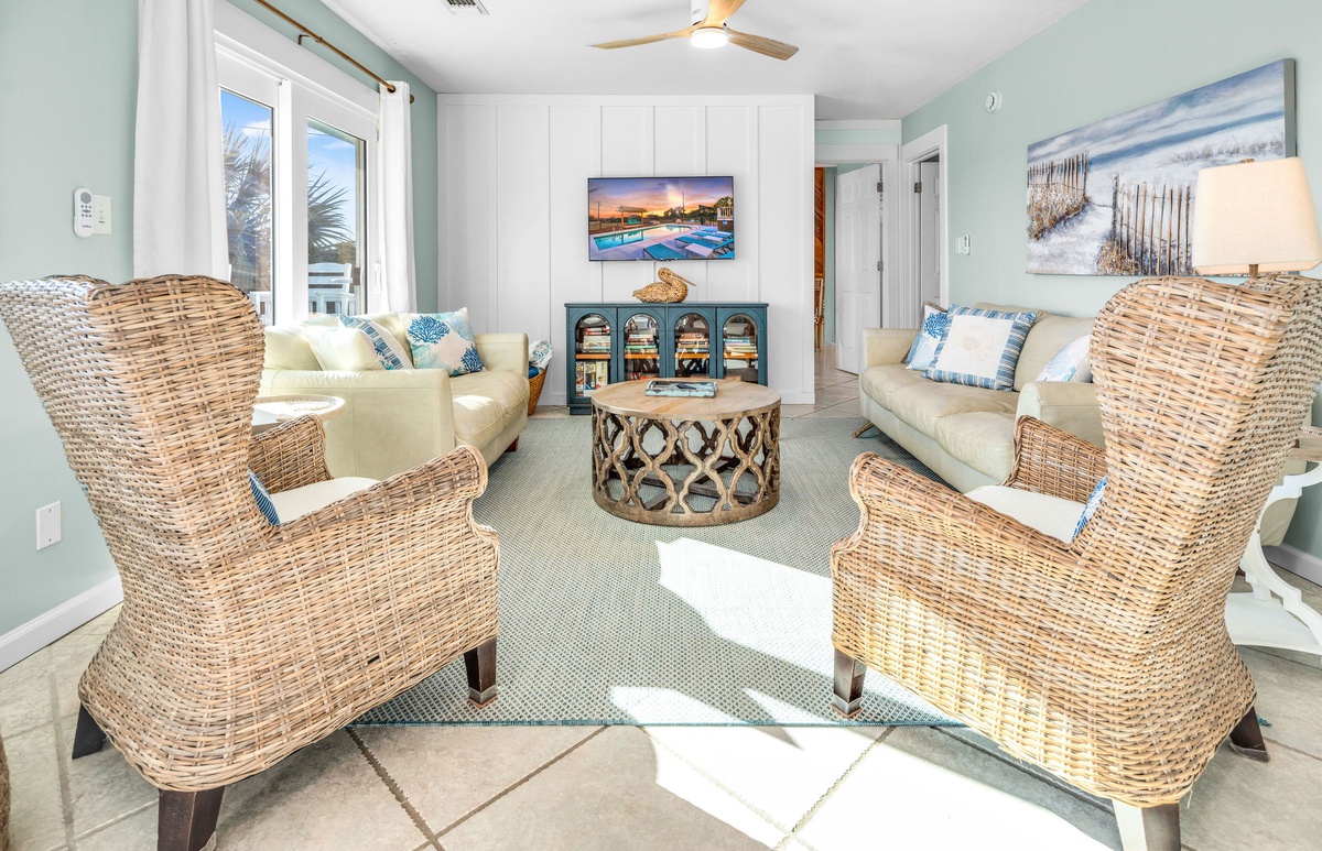 Sink into coastal comfort in your serene living space, where wicker chairs and ocean artwork create the perfect beach house retreat.
