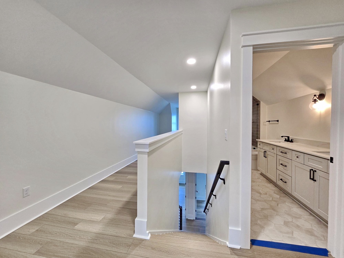 Your upstairs hallway connects beautifully to the master suite, featuring warm wood floors and elegant white railings overlooking the home below.