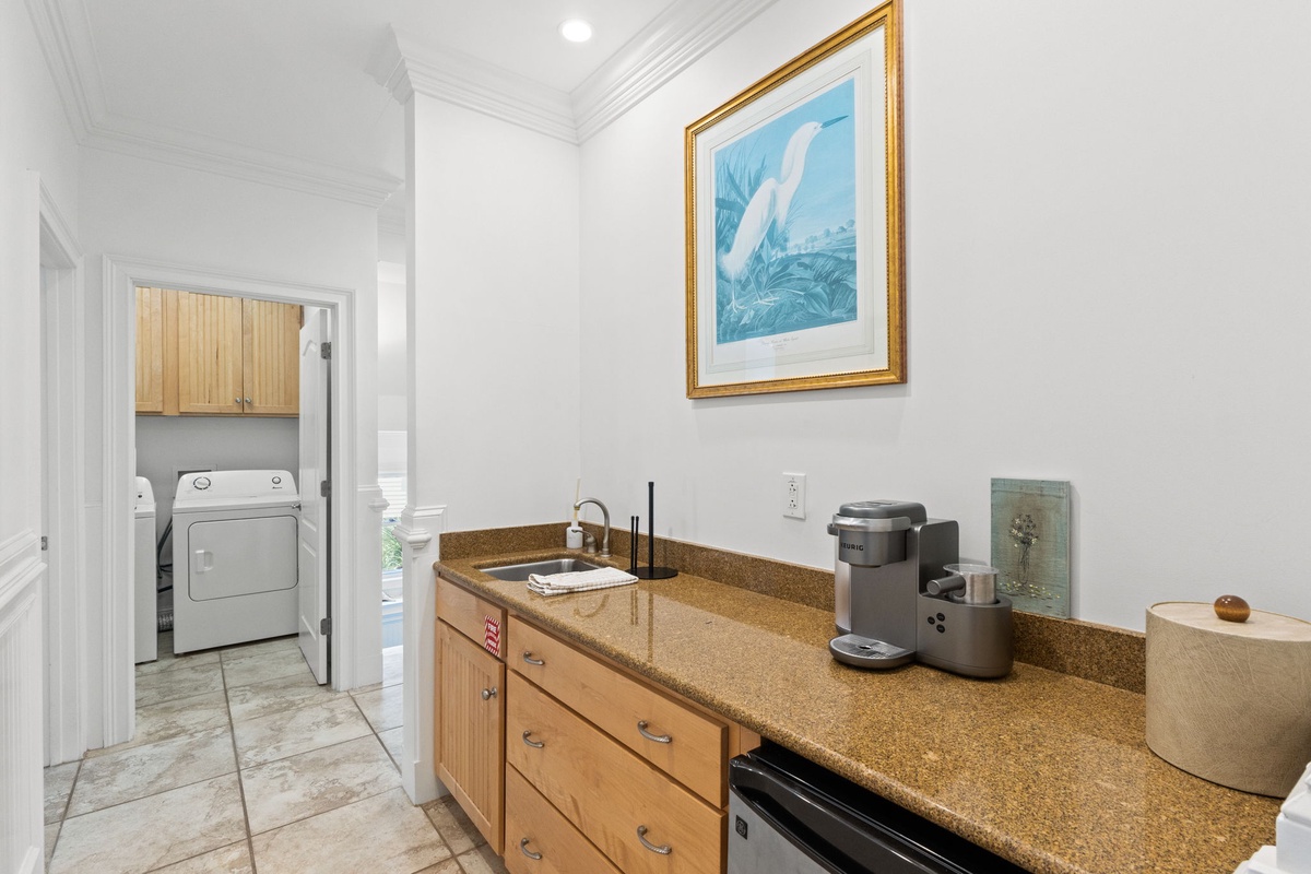 This convenient kitchenette features everything you need for quick refreshments, including a coffee maker, sink, and compact refrigerator. The adjacent laundry area adds extra comfort to your stay.