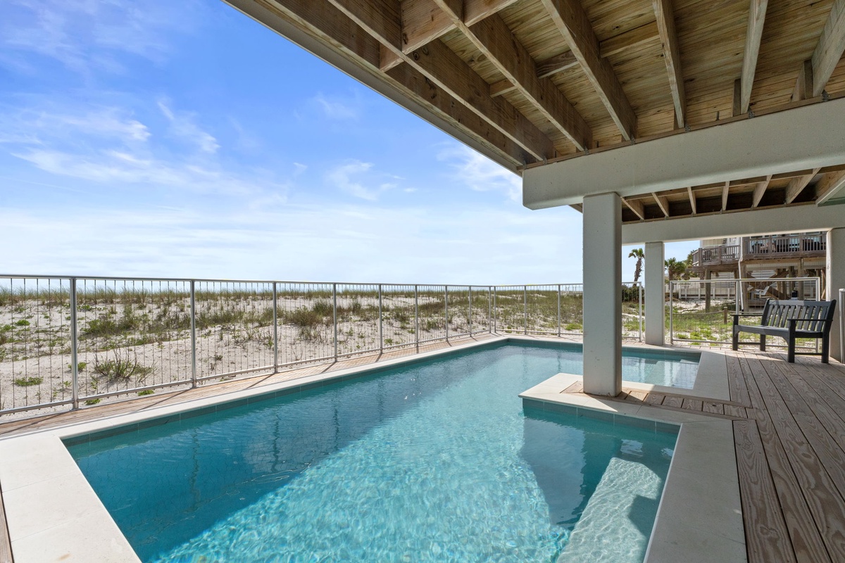Sparkling private pool framed by coastal dunes and ocean breezes, your covered deck ready with lounge chairs for sunlit relaxation steps from the shore.