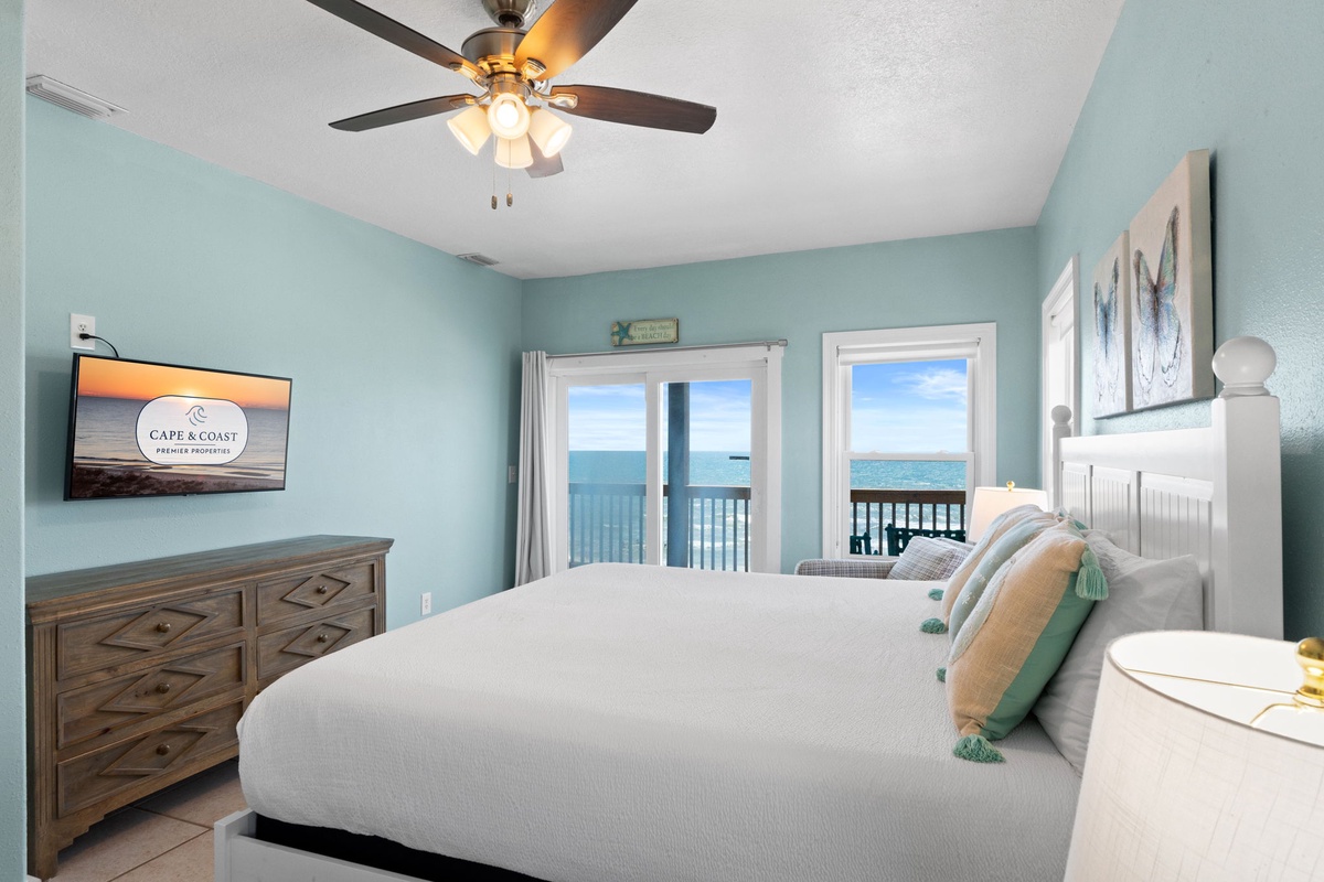 Wake up to breathtaking ocean views through your own private balcony doors. Soft coastal hues and a ceiling fan create your perfect beachfront retreat.