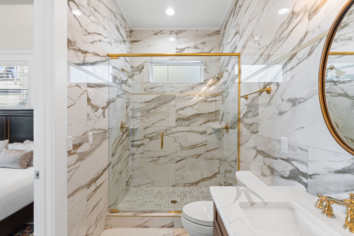 Step into your luxurious marble bathroom where elegant gold fixtures complement stunning veined walls for a spa-like retreat.
