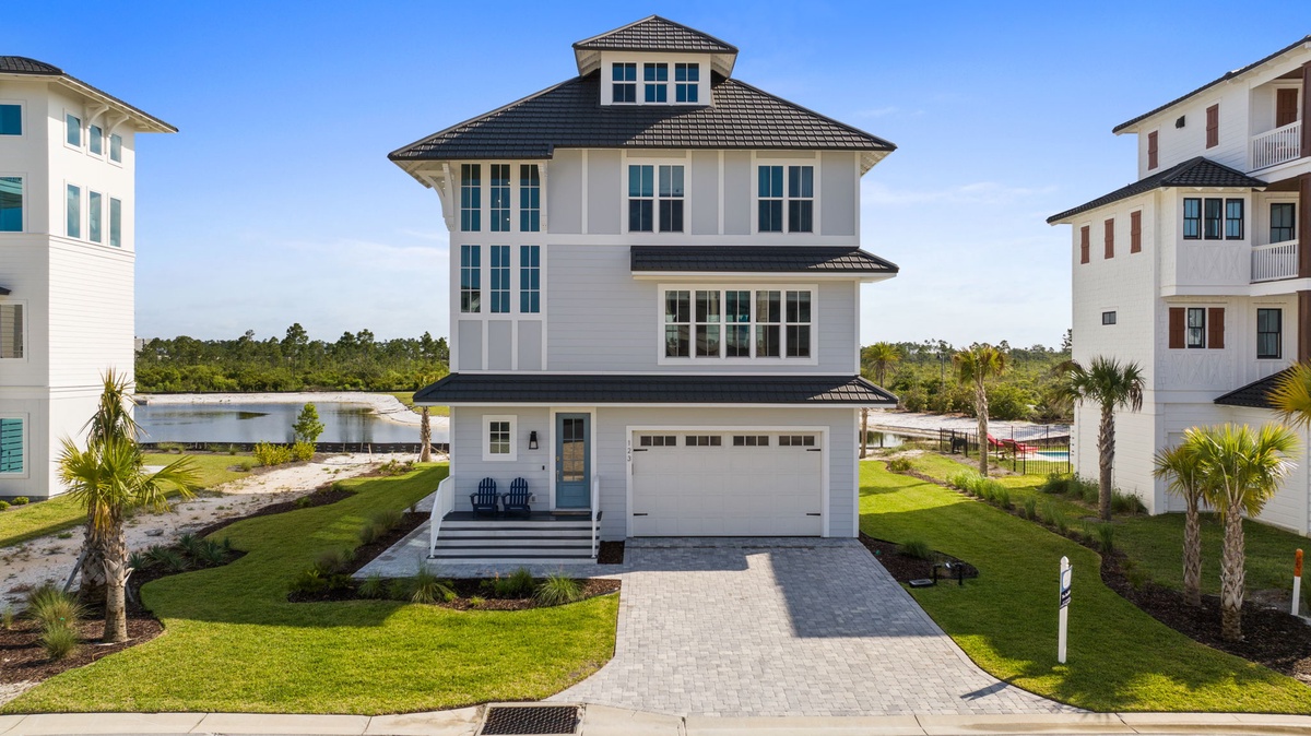Modern coastal property situated in a quiet residential neighborhood, featuring a distinctive tower design and manicured landscaping with palm trees framing the front entrance.