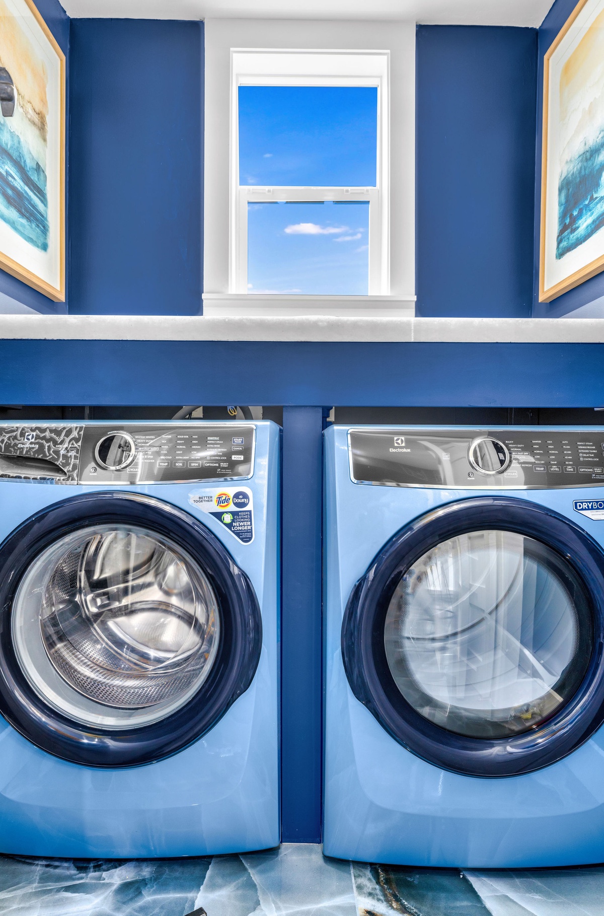 Keep your wardrobe fresh in this stylish laundry room with full-size washer and dryer, plus ocean-themed artwork.