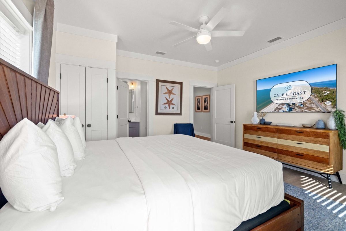 Your serene bedroom retreat features plush linens, modern coastal décor, and a ceiling fan for peaceful nights.