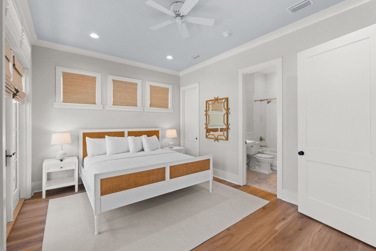 Slip into crisp white linens beneath a soothing ceiling fan, where warm coastal accents and your private ensuite bath promise restful nights in this airy, light-filled bedroom.