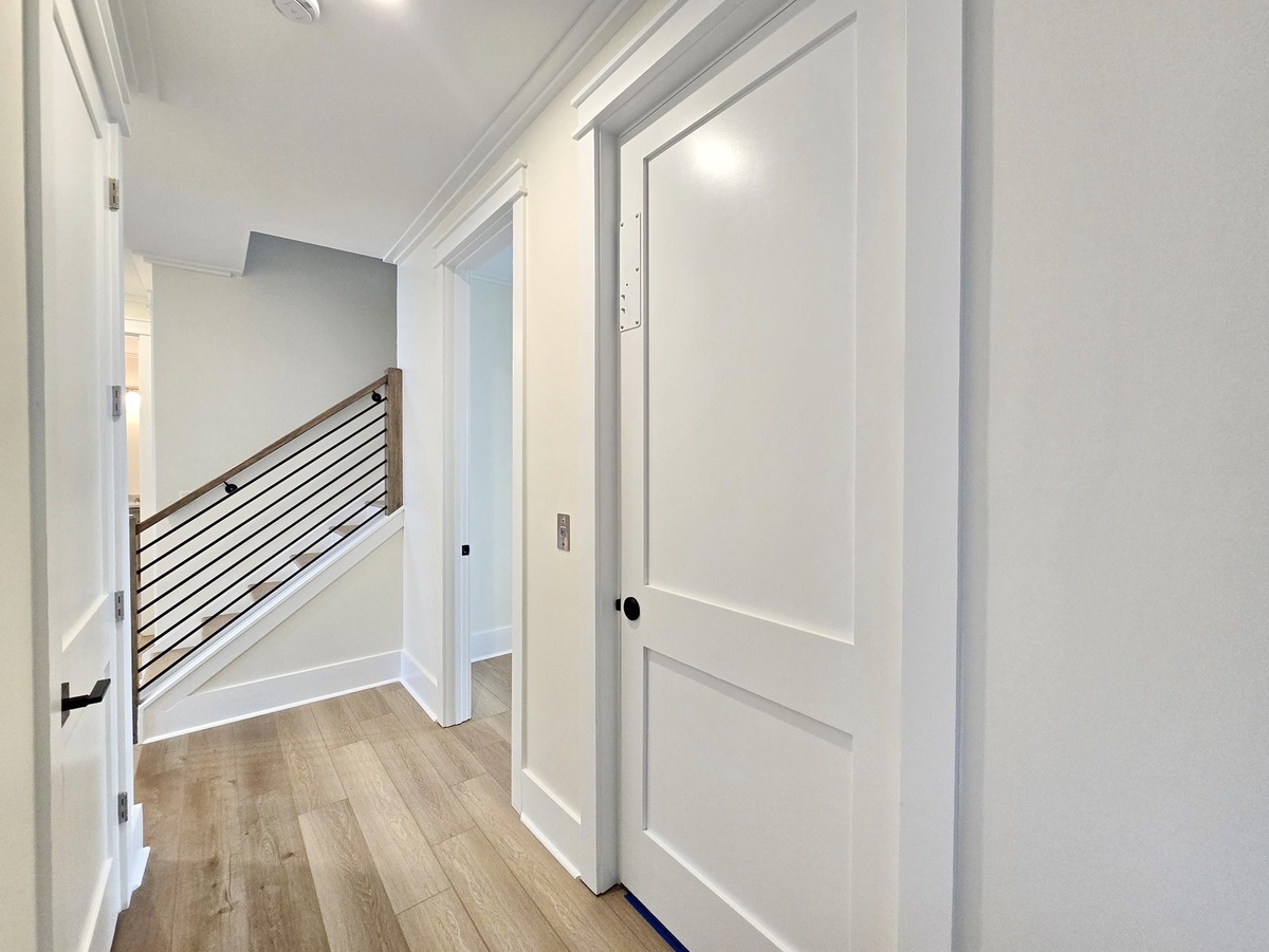 Step into your bright, modern hallway where crisp white walls and warm wood floors create a welcoming atmosphere throughout your home.