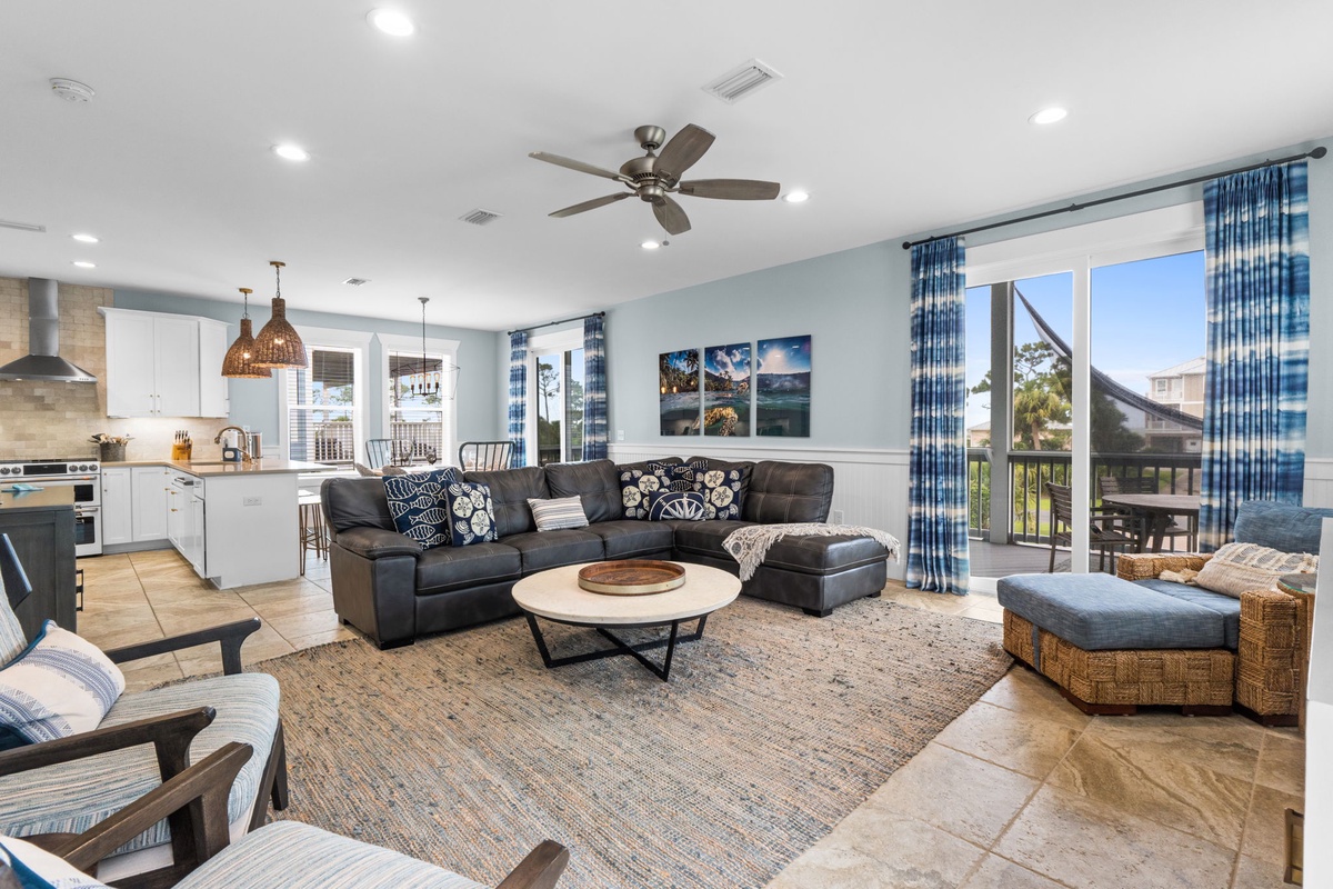 Picture yourself unwinding on the plush sectional while the ceiling fan gently circulates a cool breeze. The open-concept living room flows seamlessly into your fully-equipped kitchen, perfect for preparing meals and gathering together.
