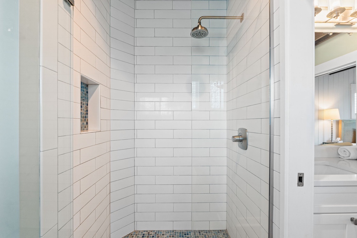 Step into your private spa-like escape with sleek subway tile, a rainfall showerhead, and custom niche for your toiletries—all bathed in natural light.