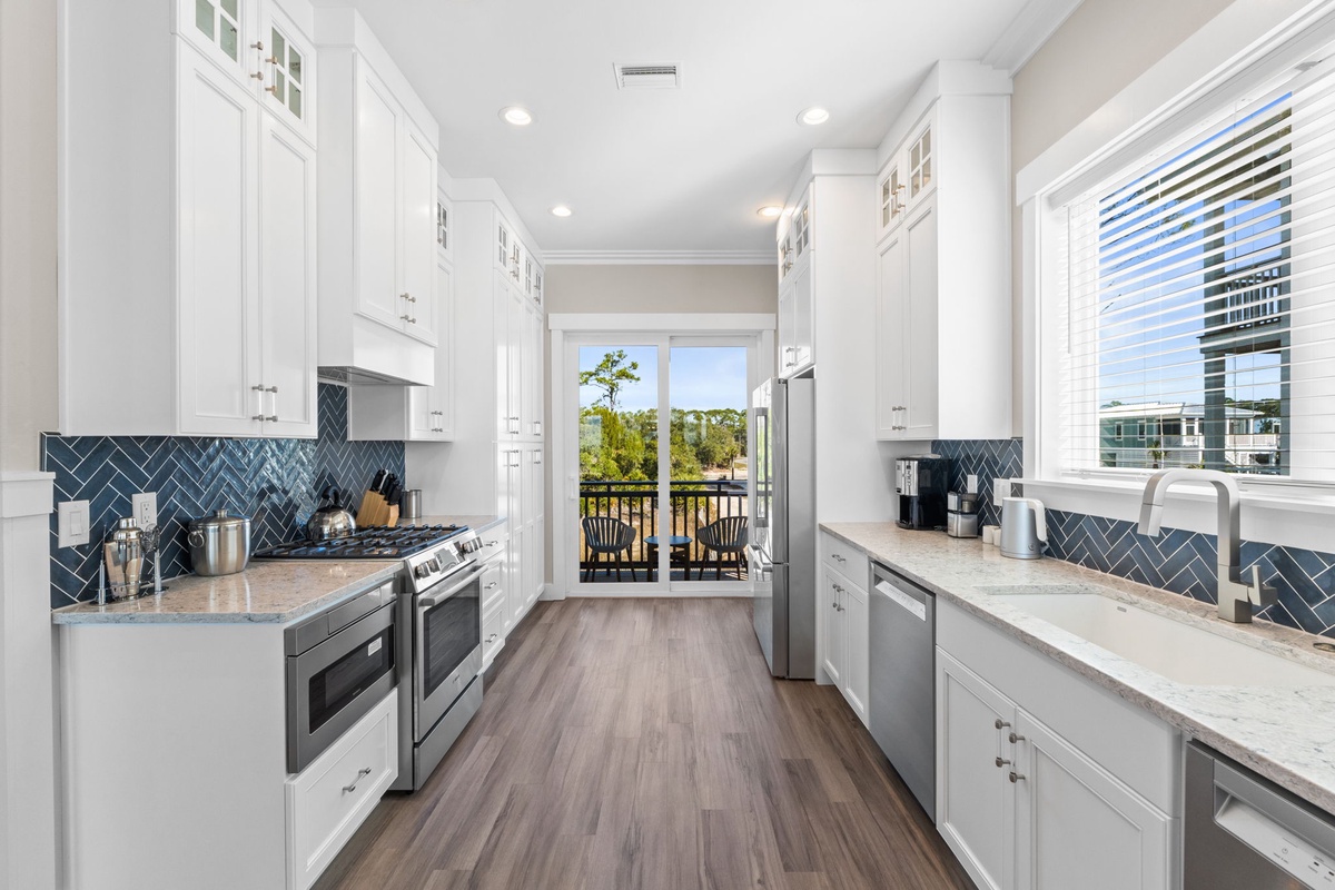 Cook with ease in your bright, fully-equipped kitchen featuring marble countertops, stainless steel appliances, and beautiful blue herringbone backsplash.