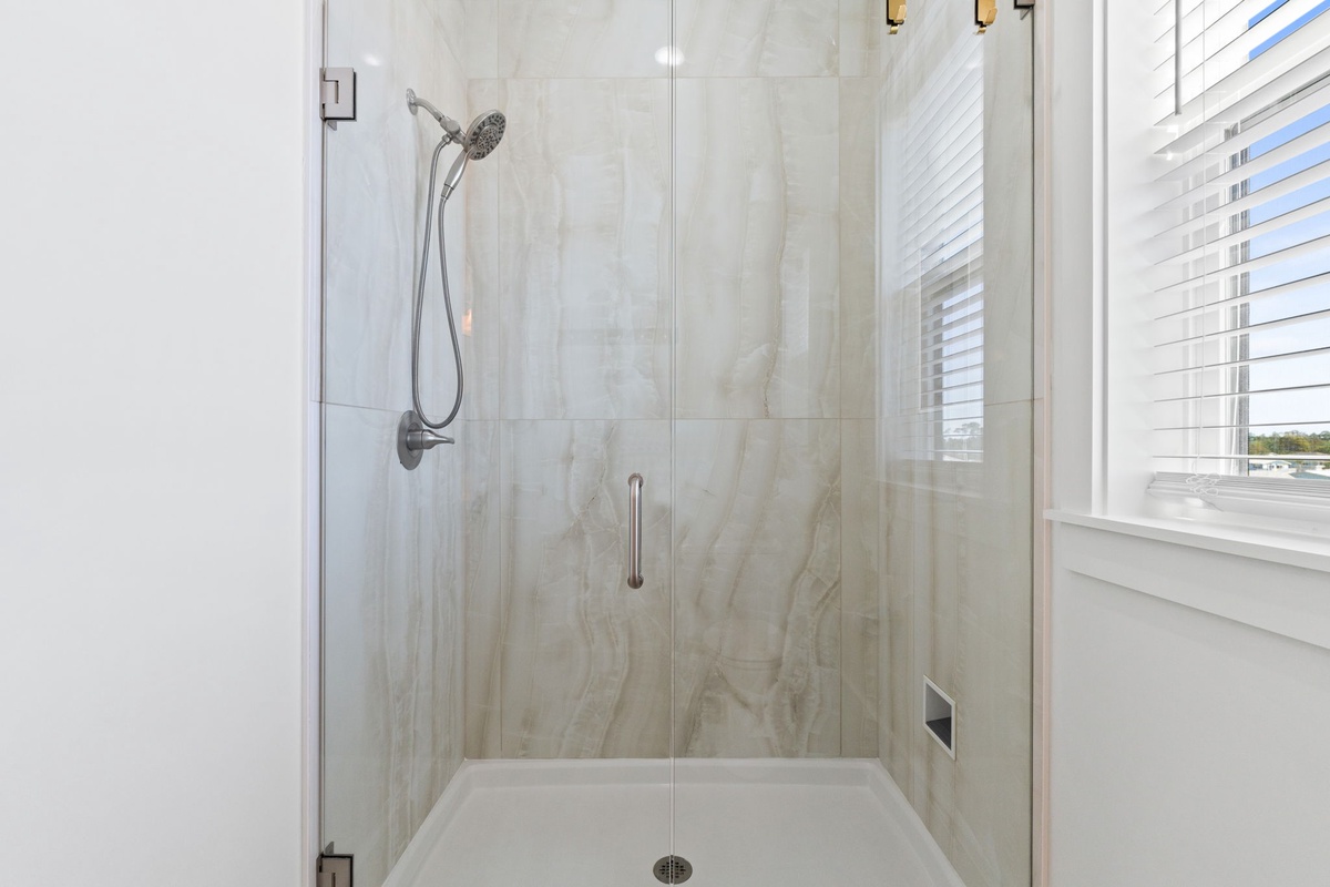 Step into your luxurious glass-enclosed shower with elegant marble walls and modern fixtures for a refreshing start to your day.