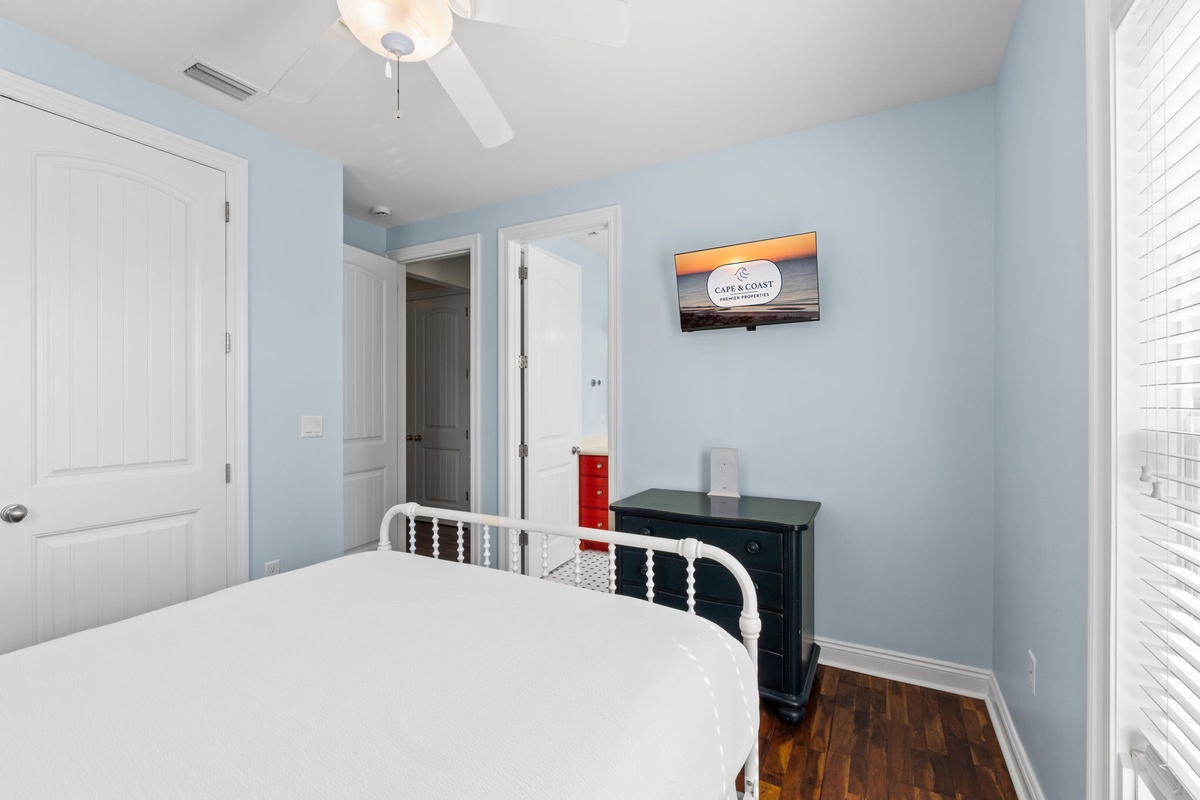 Relax in your peaceful bedroom with soft blue walls, a plush bed, and a gentle ceiling fan keeping you comfortable. The TV and coastal touches make it easy to unwind after your adventures.