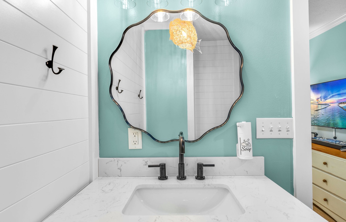 Refresh in your stylish bathroom featuring elegant coastal colors, a statement mirror, and marble finishes.