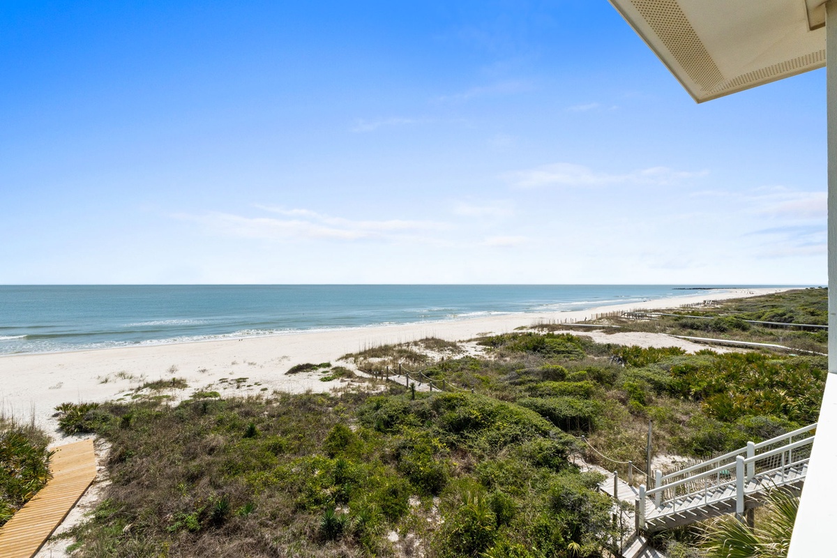Spectacular beachfront location with pristine white sand, rolling waves, and lush coastal vegetation extending along the shoreline.