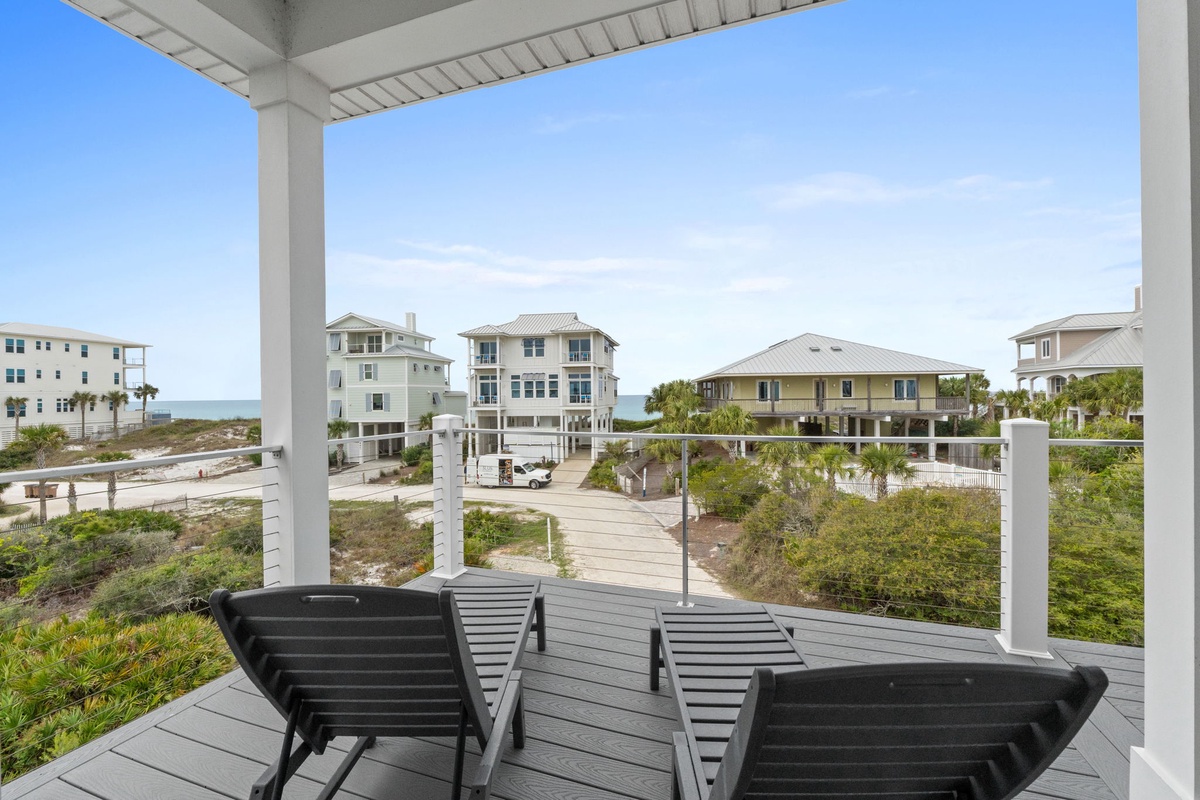 Unwind on your private covered deck with ocean glimpses and coastal views stretching beyond charming beach homes.