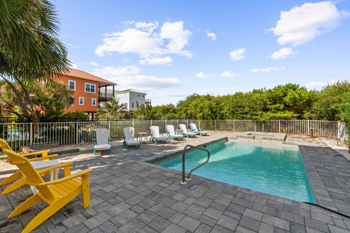 Sparkling pool surrounded by colorful lounge chairs and lush greenery, just steps from the beach. Your perfect spot to soak up the Florida sunshine and unwind in paradise.