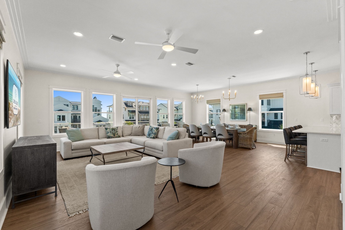 Bright, open living space with large windows, natural light, and ceiling fans. Seamless flow from inviting seating to dining—perfect for vacation gatherings.