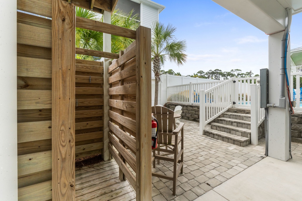 Step out to your private patio with brick pavers, outdoor shower, and inviting rocking chair beneath swaying palm trees—perfect for unwinding after beach days.