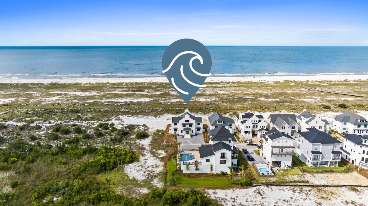 Aerial view of a beachfront vacation community nestled between natural dunes and the turquoise Gulf waters, just steps from the sand.