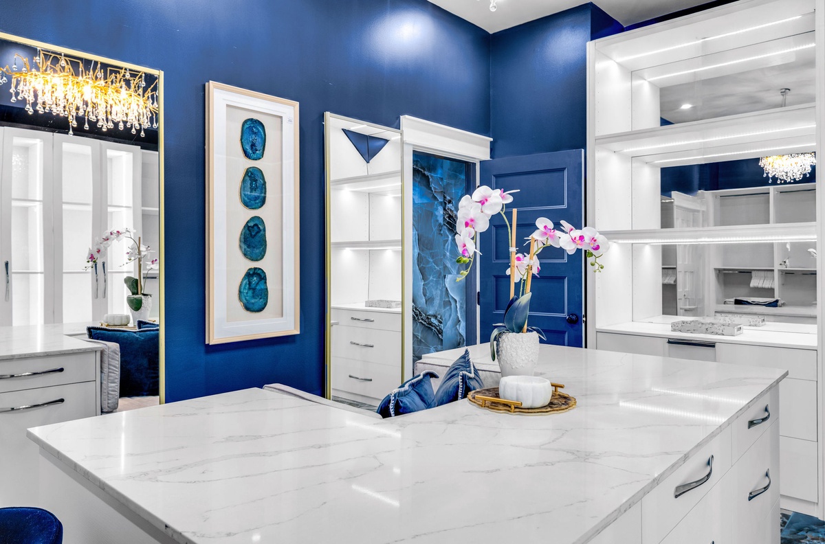 Cook in this stunning white kitchen featuring bold blue walls, marble countertops, and elegant crystal chandeliers that make every meal feel special.