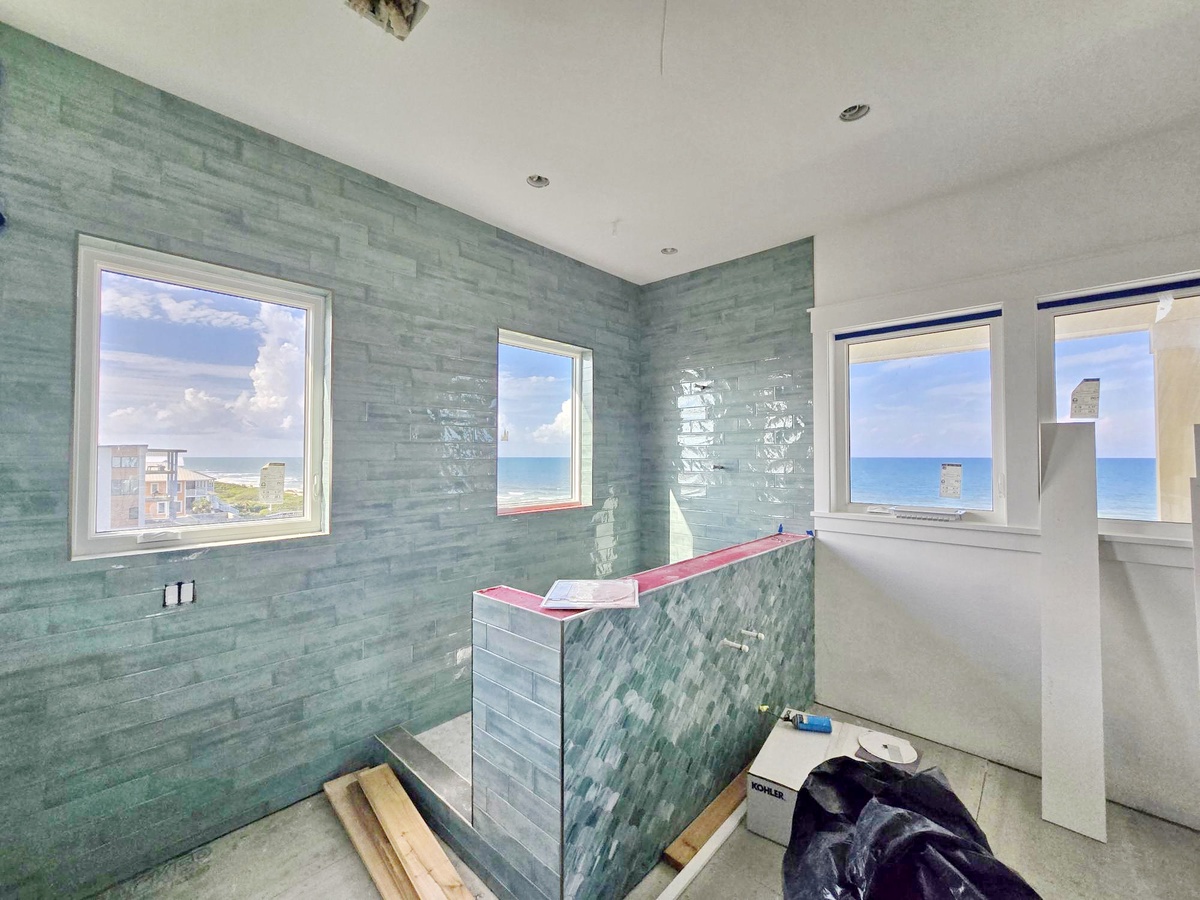 Watch the ocean waves from your spacious shower with stunning sea views through large windows, all wrapped in soothing seafoam tile.