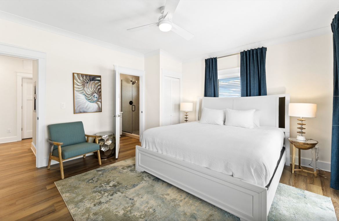 Sink into crisp white linens and enjoy the gentle ceiling fan breeze in your serene bedroom retreat with stylish coastal touches.