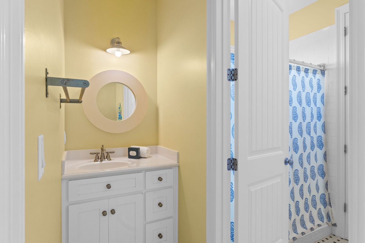 Your bright, cheerful bathroom awaits with crisp white fixtures, a charming round mirror, and coastal touches that bring beachy vibes indoors.