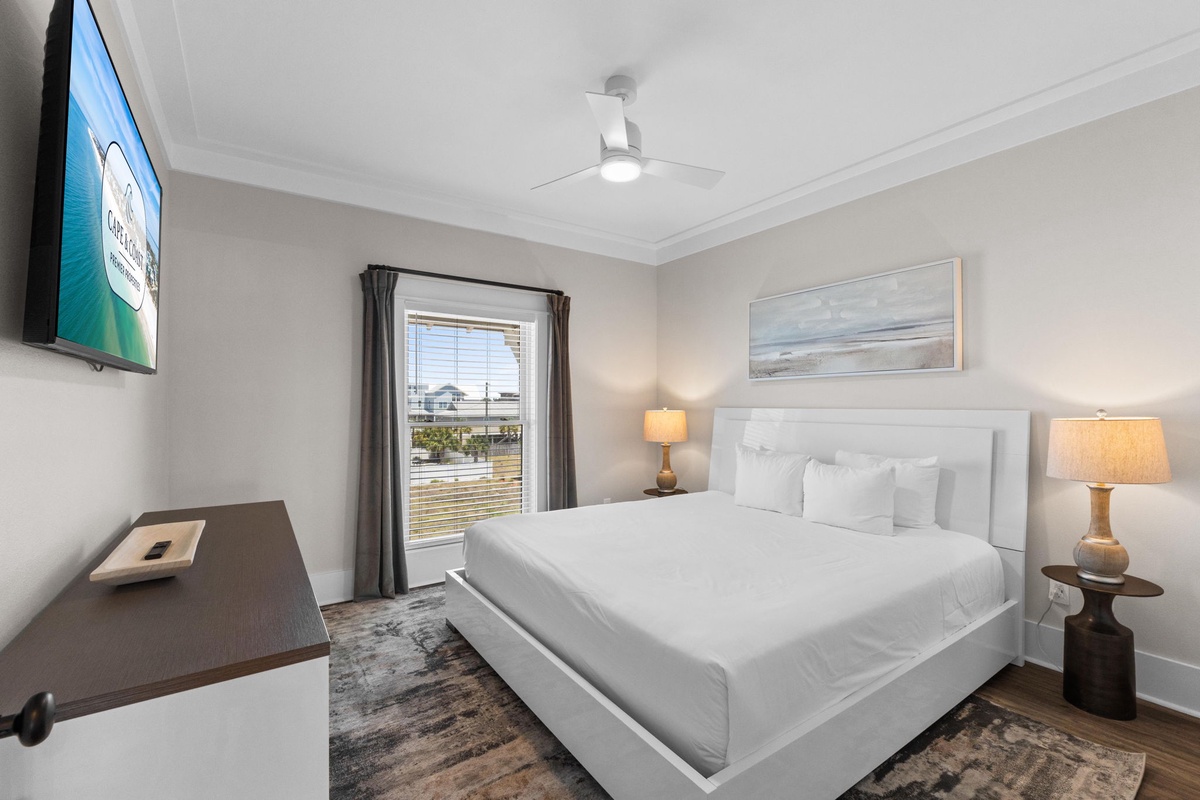 Sink into crisp white linens and wake refreshed in your serene bedroom, complete with a wall-mounted TV and calming coastal artwork above your plush bed.