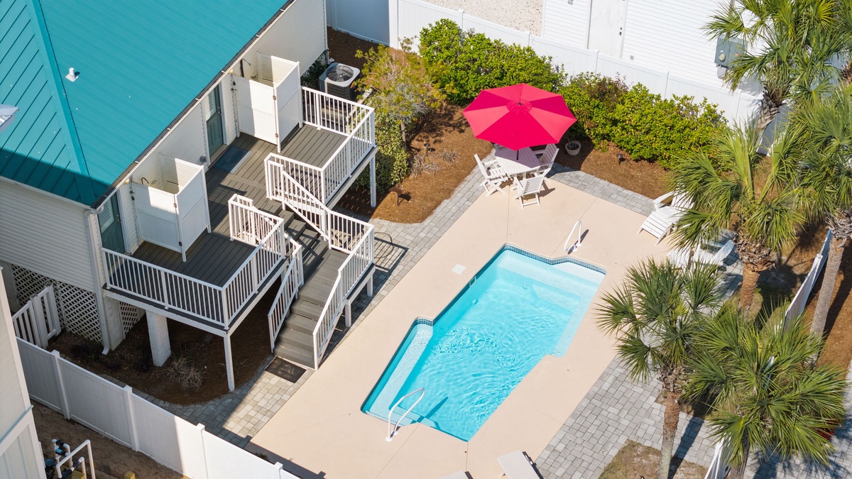 Aerial view of vacation rental property featuring private pool, tropical landscaping, and multi-level deck structure in coastal setting.