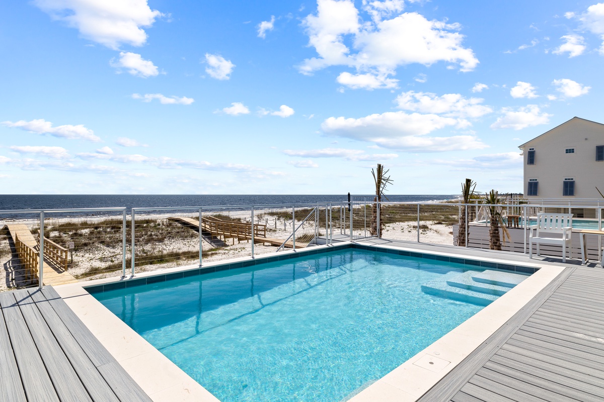 Sparkling pool deck with stunning ocean views and direct beach access via boardwalk.
