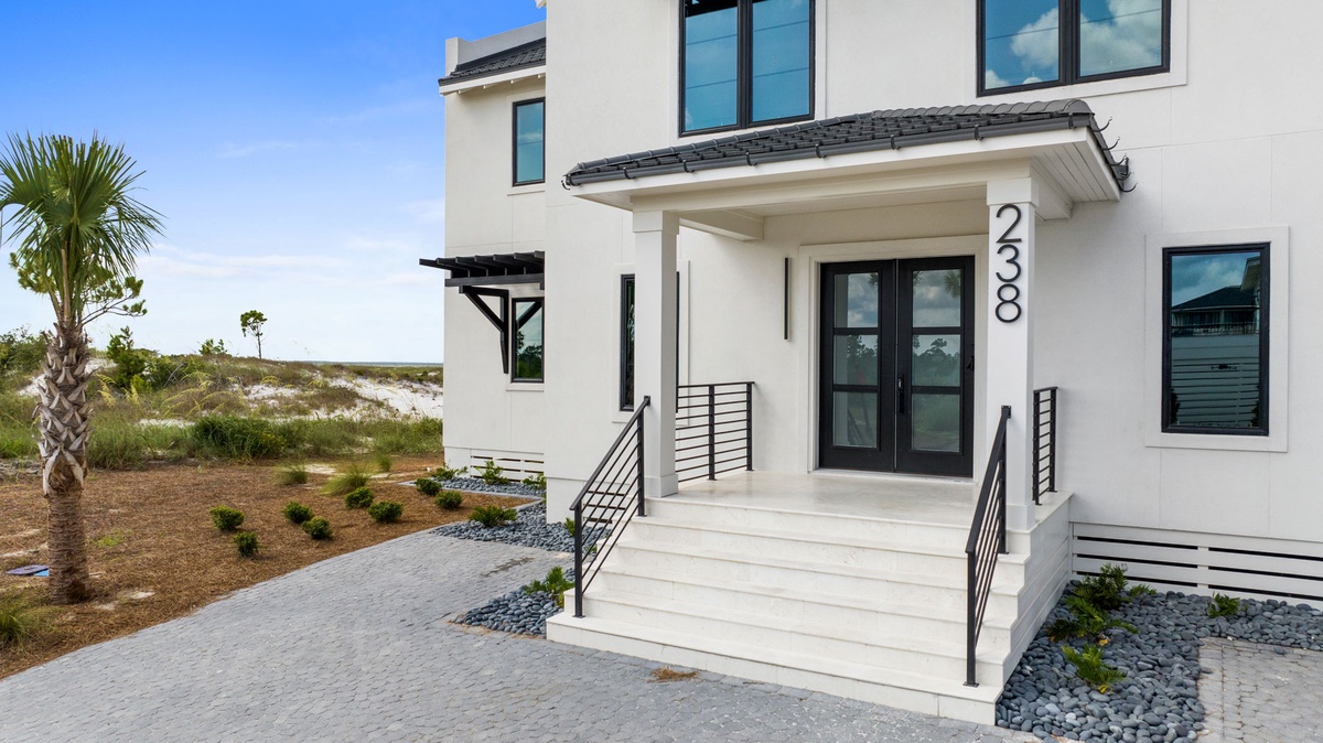 Modern coastal property features clean architectural lines, natural landscaping with palm trees, and convenient access to nearby coastal areas and natural surroundings.
