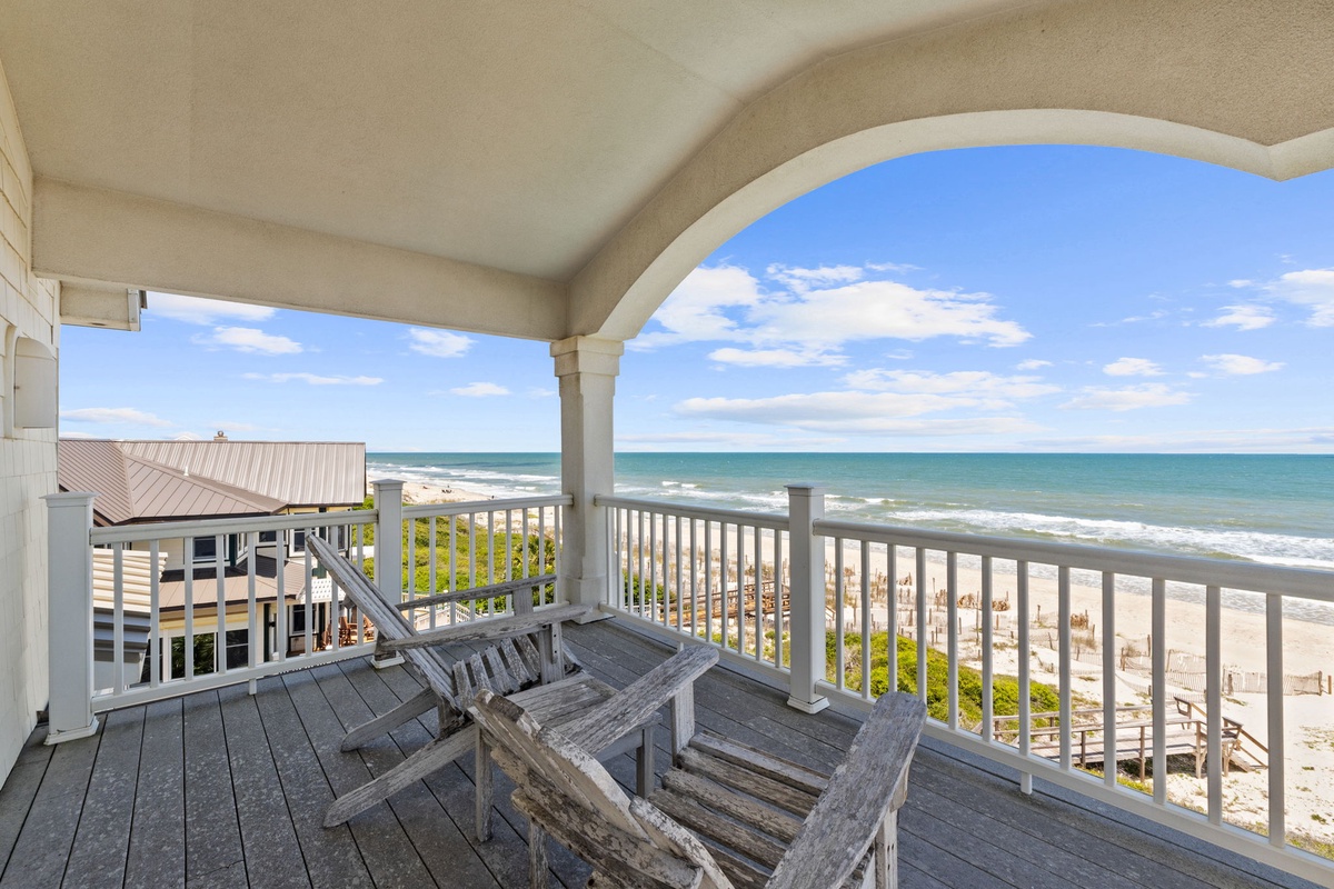 Oceanfront covered balcony frames sweeping views of turquoise waters and soft sand, with comfortable lounge chairs inviting you to sip morning coffee and watch waves roll ashore in complete coastal serenity.