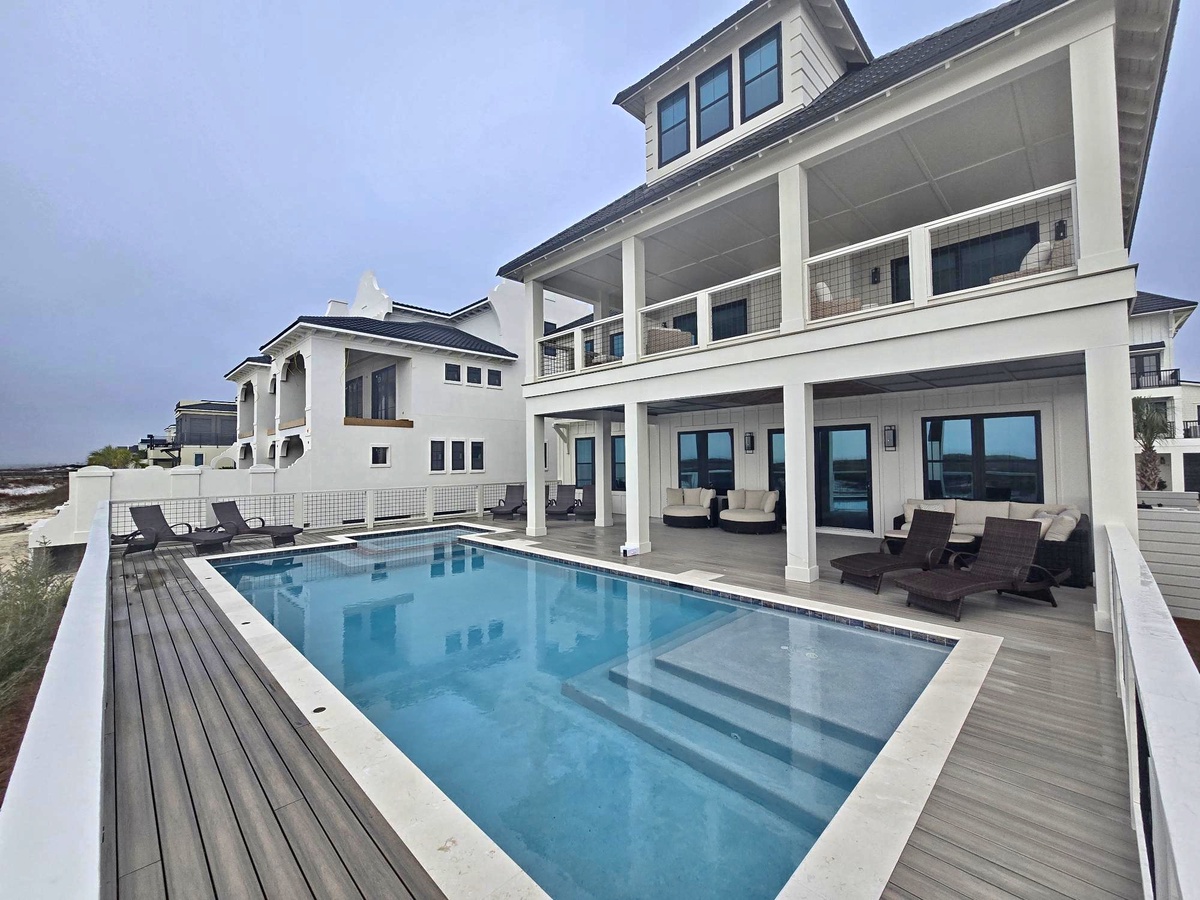 Modern coastal home featuring a private pool, expansive deck, and covered terraces with outdoor seating areas.