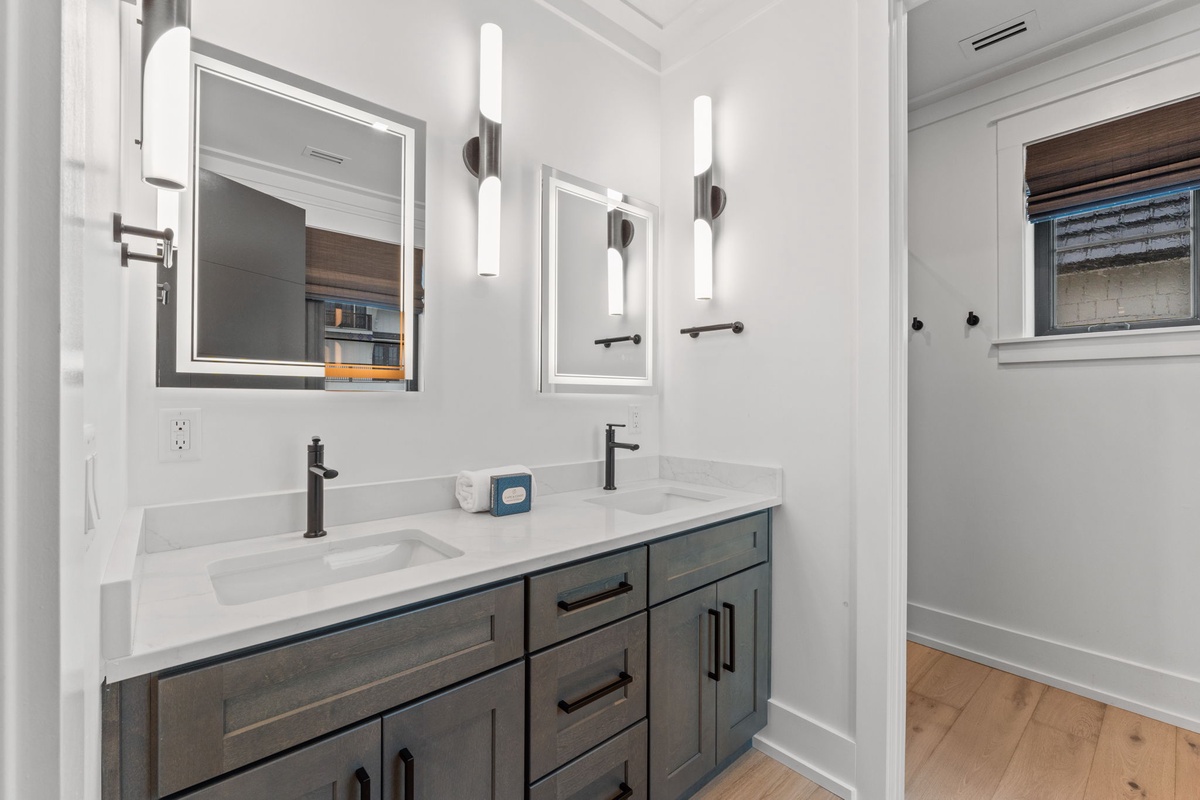 You'll love getting ready in this bright, modern double vanity bathroom with elegant lighting and ample storage in the stylish wood-toned cabinetry.